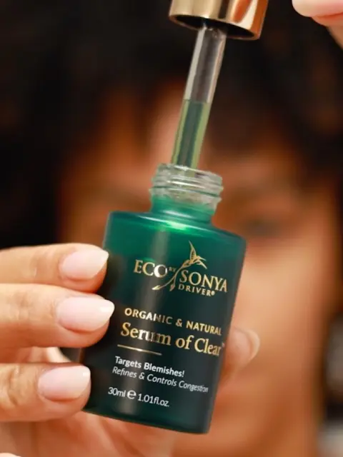Person holding Eco by Sonya Driver Serum of Clear bottle with dropper.