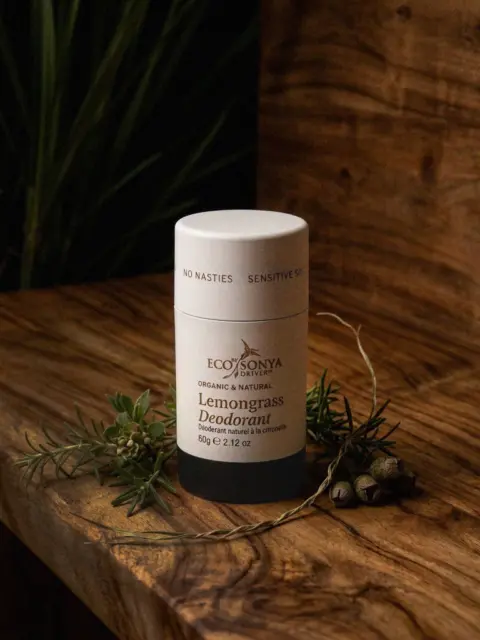 Eco by Sonya lemongrass deodorant on wooden surface with greenery.