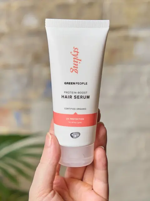 Hand holding Green People Protein-Boost Hair Serum tube.