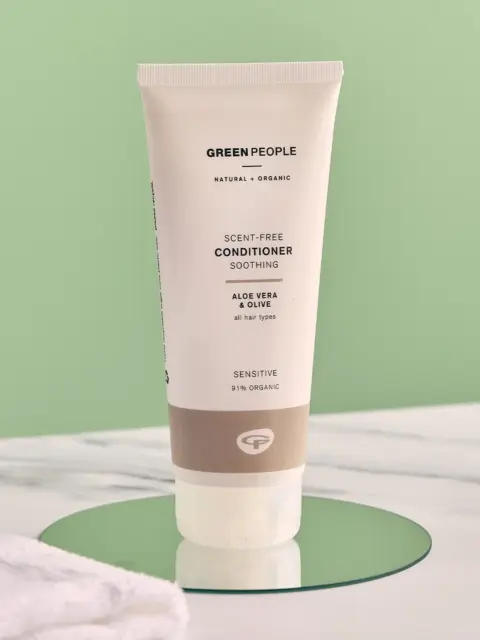 Green People scent-free conditioner tube on a green surface.