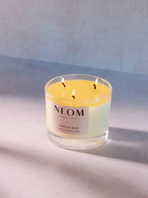 NEOM Complete Bliss candle with three wicks on a light surface.
