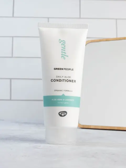 Green People Daily Aloe Conditioner tube on tiled bathroom counter.
