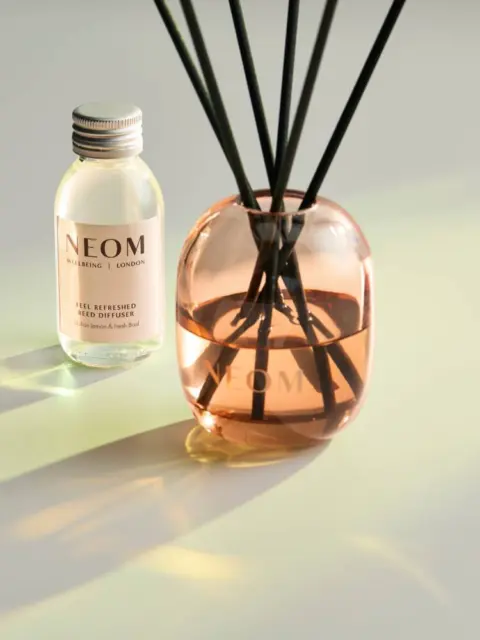 Reed diffuser and NEOM bottle on a light surface.