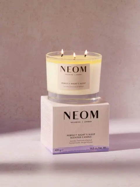 NEOM Perfect Night's Sleep scented candle on a box, lit with three wicks.