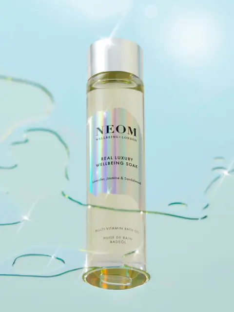 NEOM Real Luxury Wellbeing Soak bottle with shimmering water background.