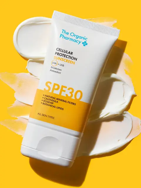 Sunscreen tube with SPF 30 on a yellow background, cream smeared behind.