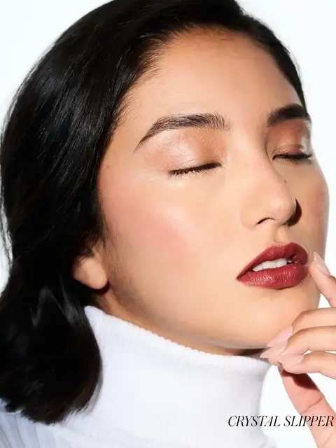 Woman with closed eyes, wearing red lipstick and white turtleneck. Text: "CRYSTAL SLIPPER".