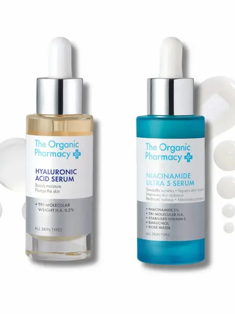 Two bottles of The Organic Pharmacy serums with droppers and liquid droplets.