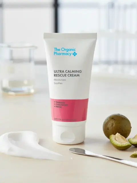 Tube of Ultra Calming Rescue Cream on table with sliced fruit and cream smear.
