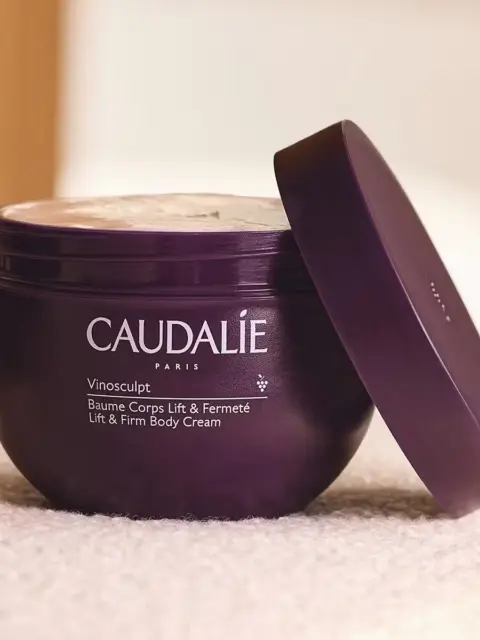 Purple jar of Caudalie Vinosculpt Lift & Firm Body Cream with lid slightly open.