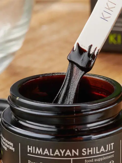 Himalayan Shilajit jar with a spatula dipped in dark paste.