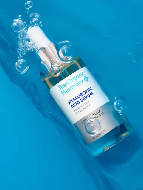 Hyaluronic Acid Serum bottle submerged in water with bubbles.