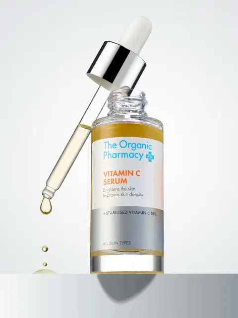 The Organic Pharmacy Vitamin C Serum with dropper and liquid droplet.