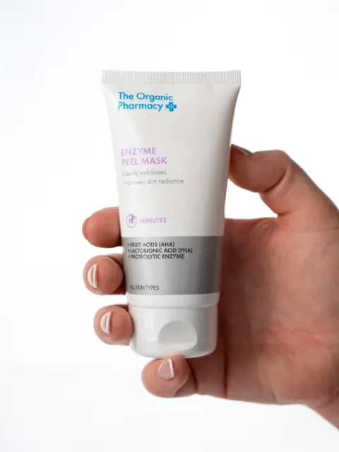 Hand holding The Organic Pharmacy Enzyme Peel Mask tube.