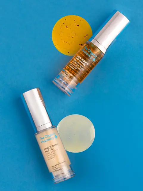 Two skincare bottles on blue background with yellow gel samples.