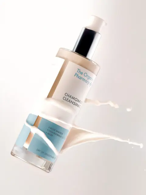 Chamomile cleansing milk bottle with liquid splash, labelled for dry or sensitive skin.