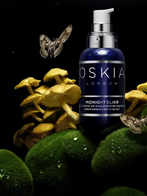 Oskia London Midnight Elixir bottle with mushrooms, moss, and moths in a dark setting.