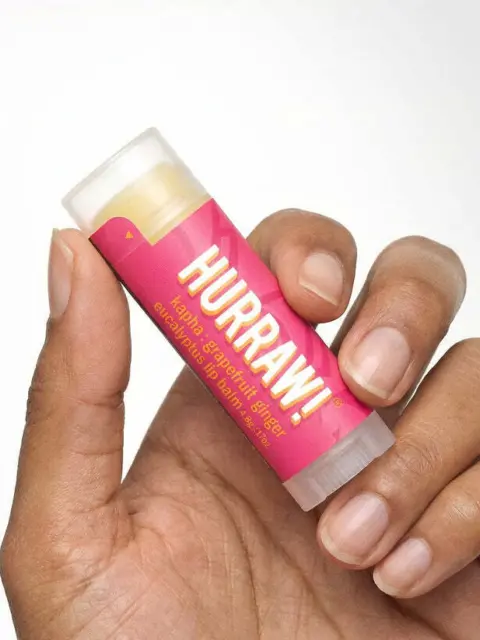 Hand holding pink Hurraw! lip balm tube.