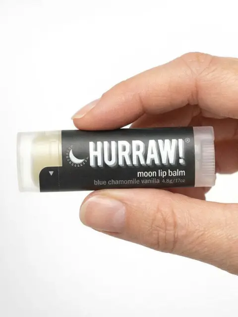 Hand holding Hurraw! moon lip balm, blue chamomile vanilla flavour.