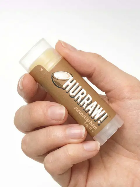 Hand holding Hurraw! coconut lip balm tube.