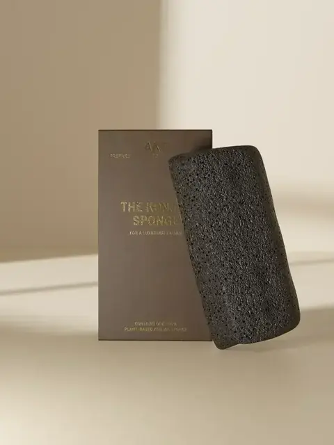 Black konjac sponge with brown packaging on a beige background.