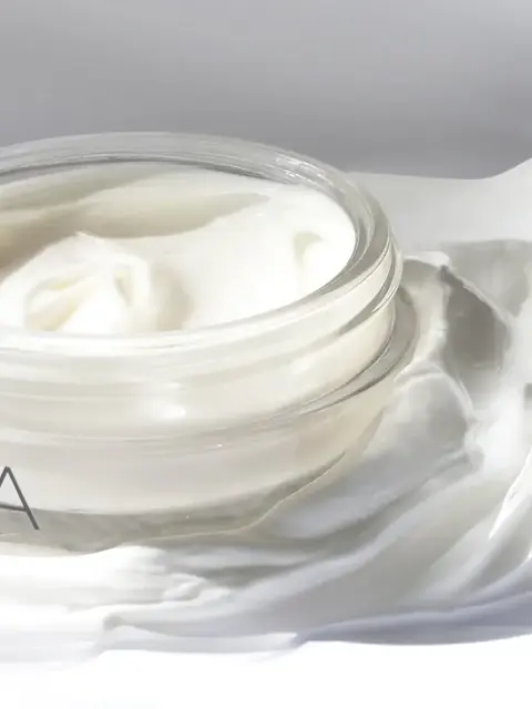 Open jar of white cream on a smooth surface.