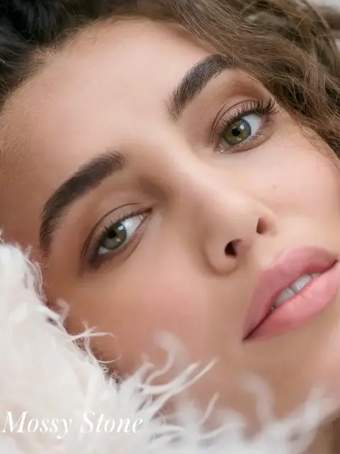 Close-up of a woman's face with curly hair and text "Mossy Stone" in the corner.