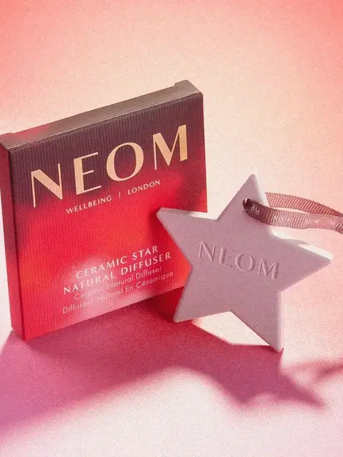 NEOM ceramic star natural diffuser with ribbon on pink background.