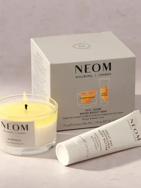 NEOM Feel Good Mood Boost Duo with candle and body butter on a light surface.