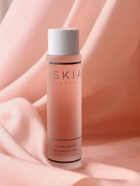 Pink bottle of Oskia London Floral Water on soft pink fabric background.