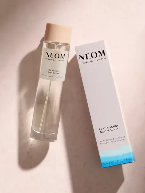 NEOM Real Luxury Room Spray bottle and box on a light surface.