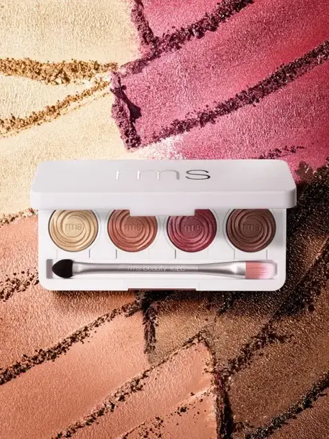 Eyeshadow palette with five shades and brush on textured background.