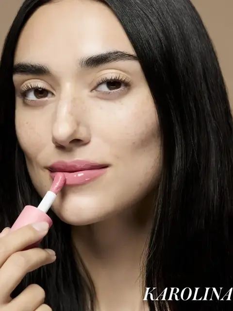 Woman applying pink lip gloss, text "KAROLINA" in corner.