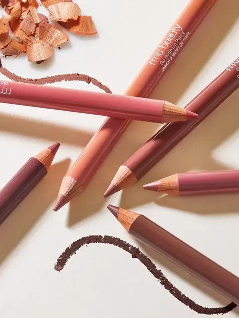 Assorted lip pencils with shavings and drawn lines on a light surface.