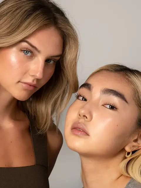 Two women with glowing skin, one with long blonde hair, the other with short blonde hair and earrings.