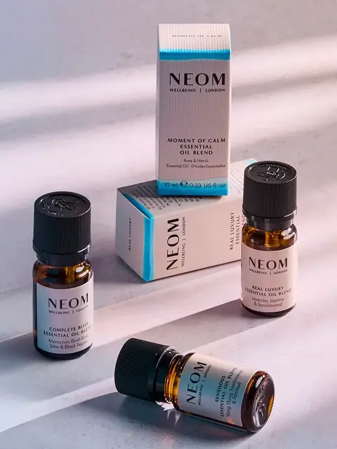 Neom essential oil bottles and boxes on a light surface.