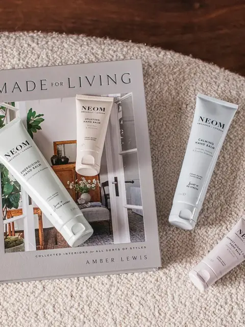 Neom hand balms on a book titled "Made for Living" by Amber Lewis on a textured surface.