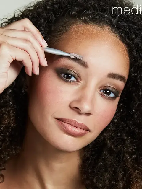 Person using eyebrow brush, text "medium" in corner.