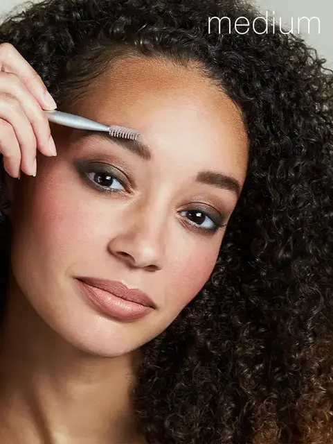 Person using eyebrow brush, text "medium" in corner.