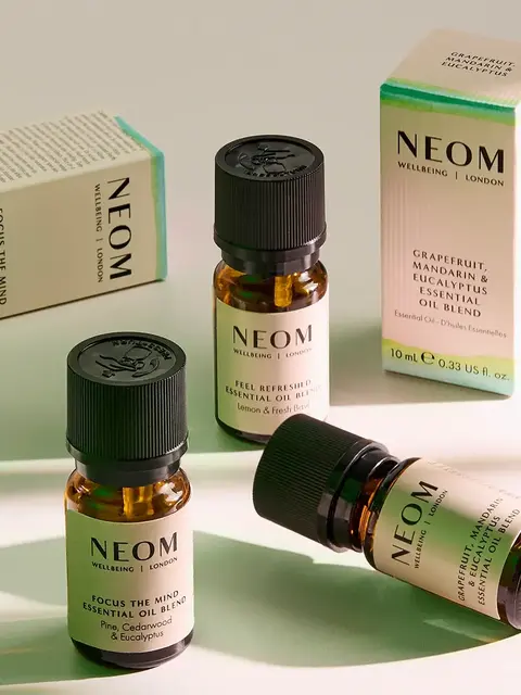 Three NEOM essential oil bottles with boxes, featuring blends like grapefruit and eucalyptus.