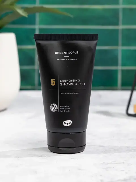 Black tube of Green People Energising Shower Gel on a white surface. Green tiled background.