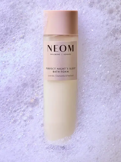 NEOM bath foam bottle on bubbly surface. Text: Perfect Night's Sleep, Lavender, Chamomile, Patchouli.
