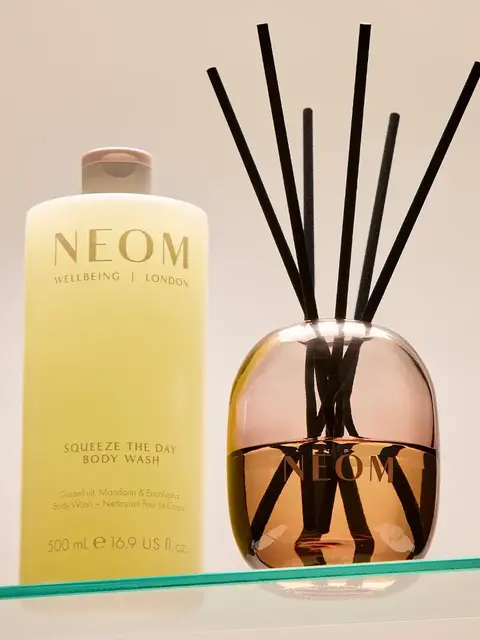 NEOM body wash and diffuser on glass shelf.