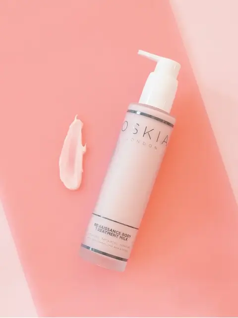 Oskia Renaissance Body Treatment Milk on pink surface with cream smear.