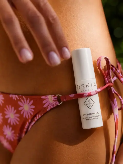 Oskia SPF Vitamin Mist bottle on floral bikini strap.