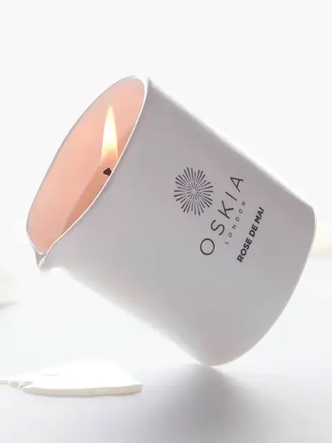 White candle labelled "OSKIA London Rose de Mai" with petals around.