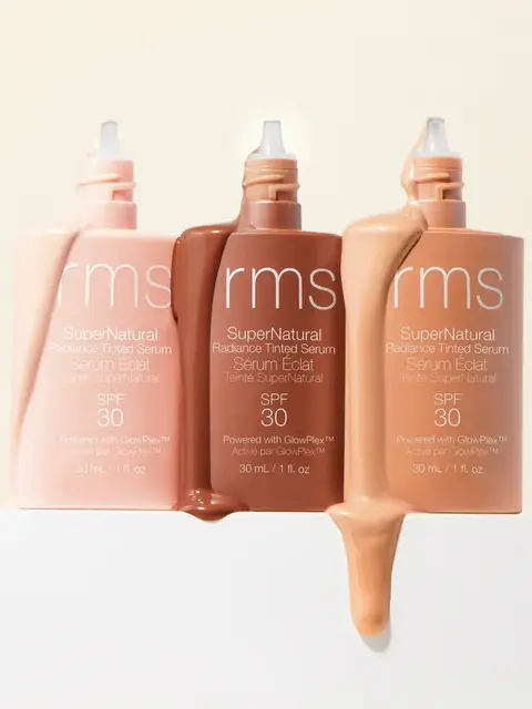 Three bottles of rms SuperNatural Radiance Tinted Serum SPF 30 in different shades.