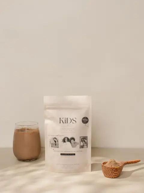 Kids nutrition powder with glass of chocolate drink and wooden scoop on a beige surface.
