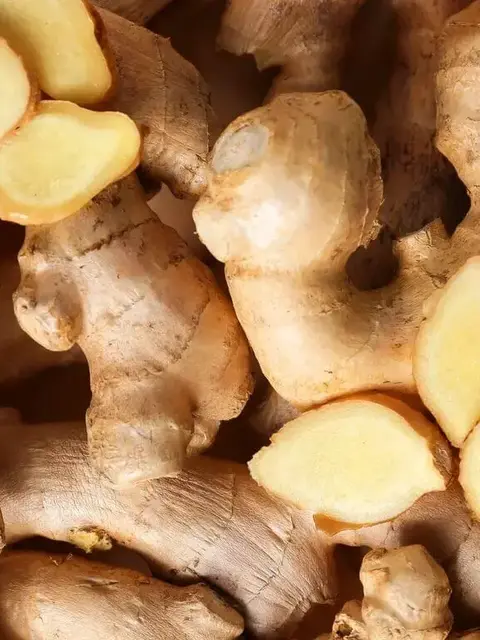 Close-up of fresh ginger roots with sliced sections showing yellow interior.