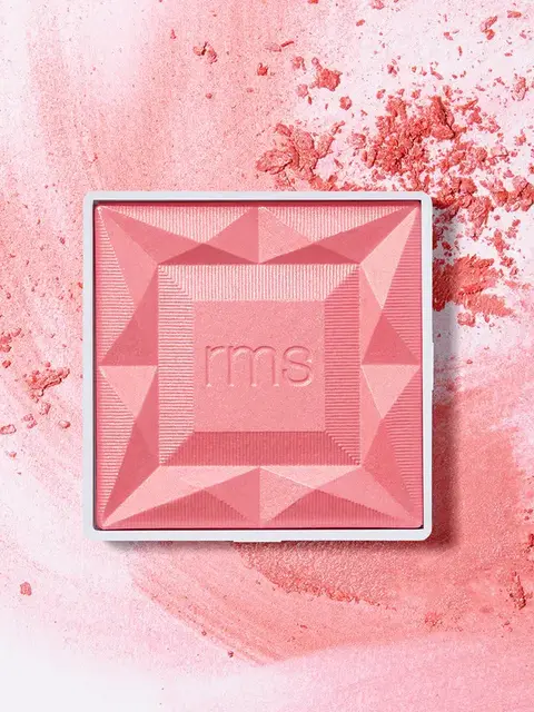 Pink blush compact with "rms" embossed, surrounded by loose powder.